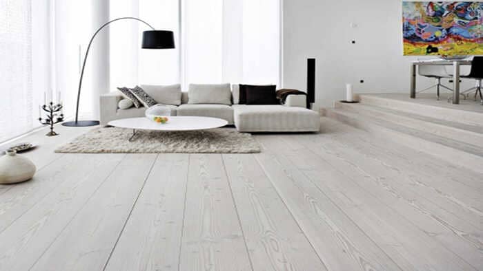 Mẫu sàn gỗ màu trầm kết hợp bộ sofa trắng sang trọng là điểm nhấn gây ấn tượng khi khách đến thăm nhà